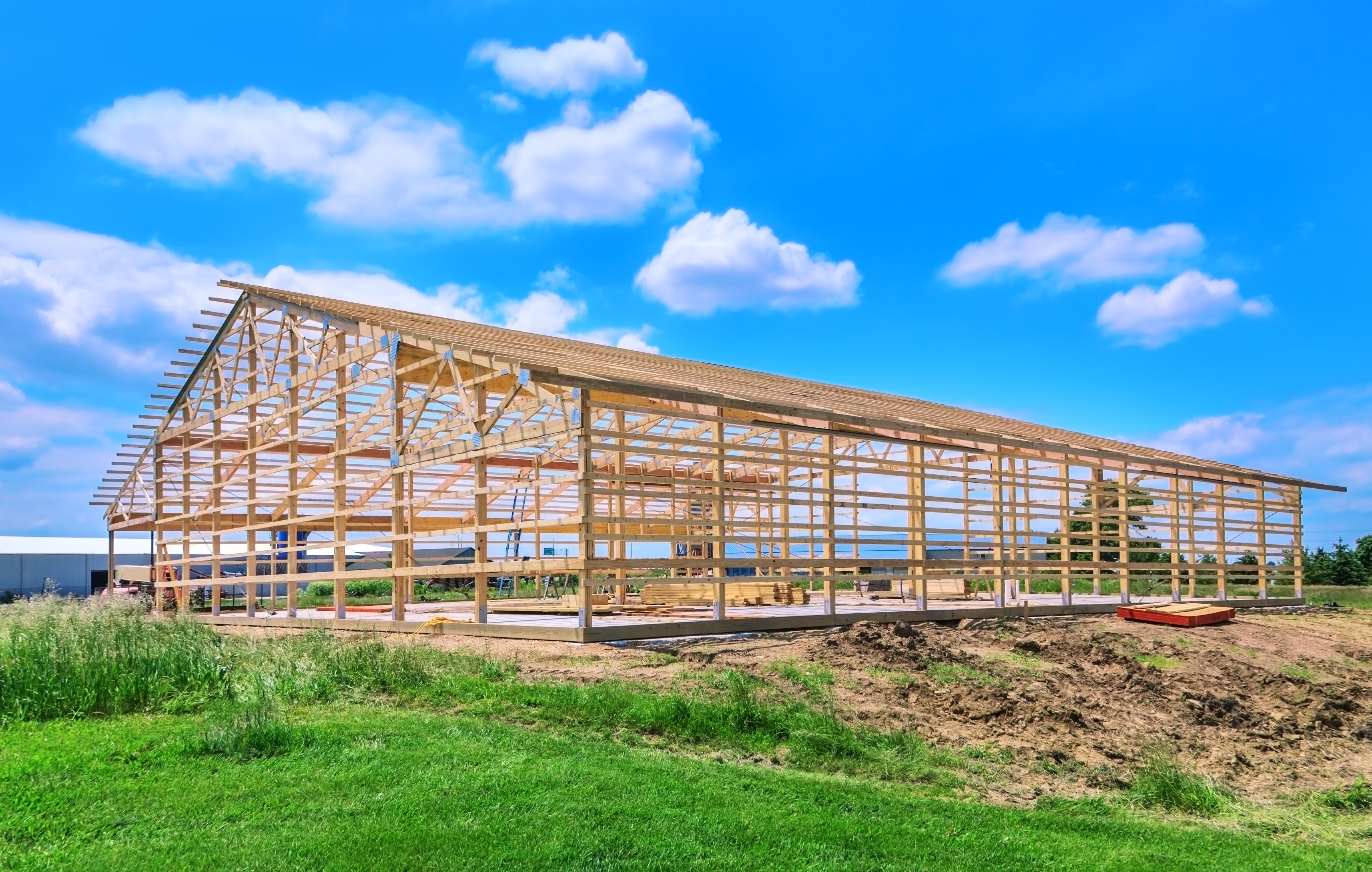 New pole barn showing wood framing, being built on a concrete sl