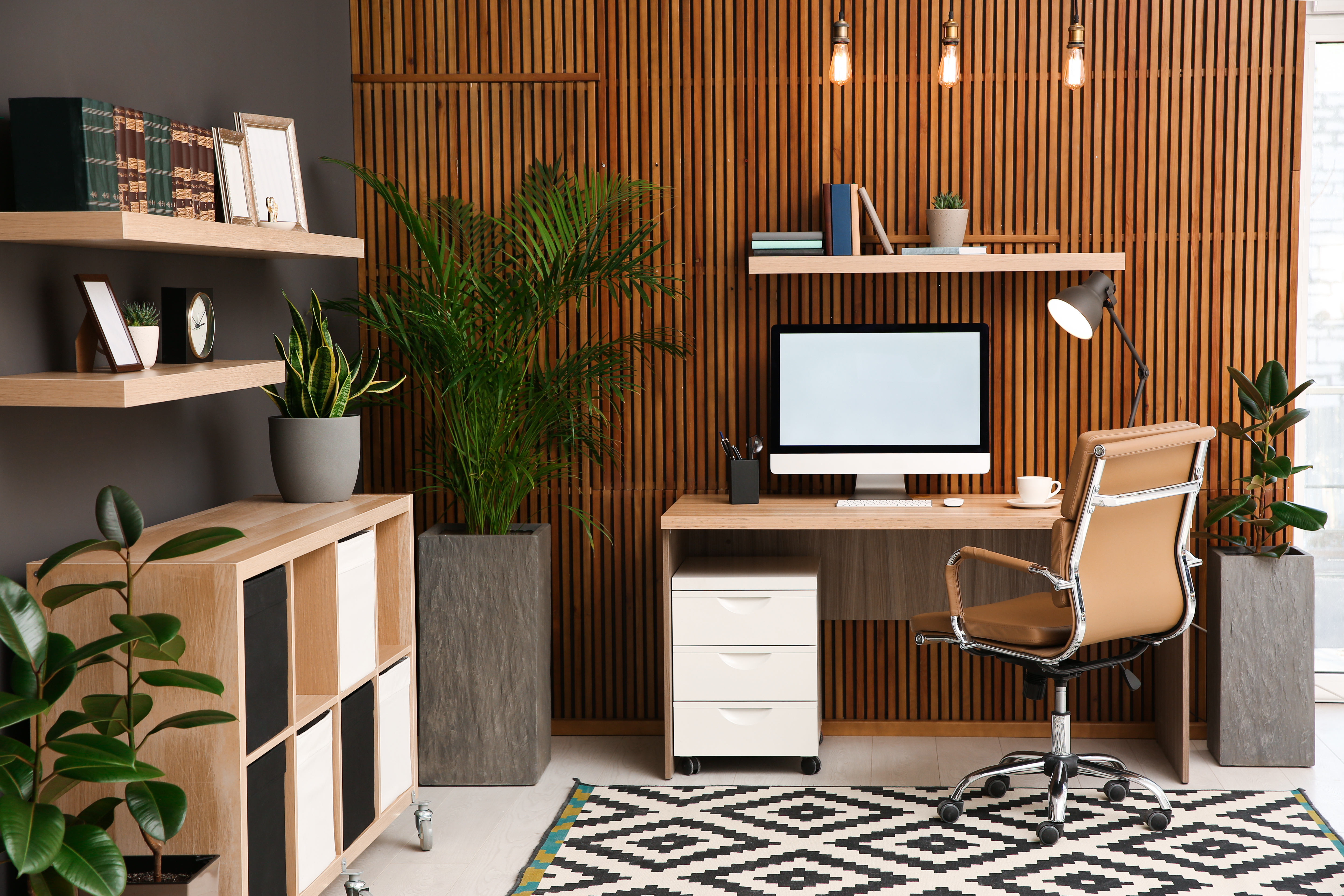 Comfortable workplace with computer near wooden wall in stylish